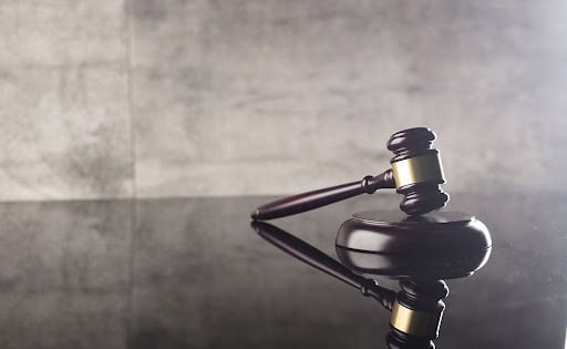 Gavel de juge en bois sur une surface sombre.