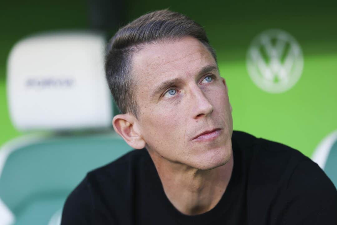 Homme pensif avec fond vert et logo Volkswagen.