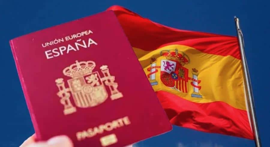 Conditions 2026 pour se régulariser sans papiers en Espagne Passeport espagnol avec drapeau national contre ciel bleu.