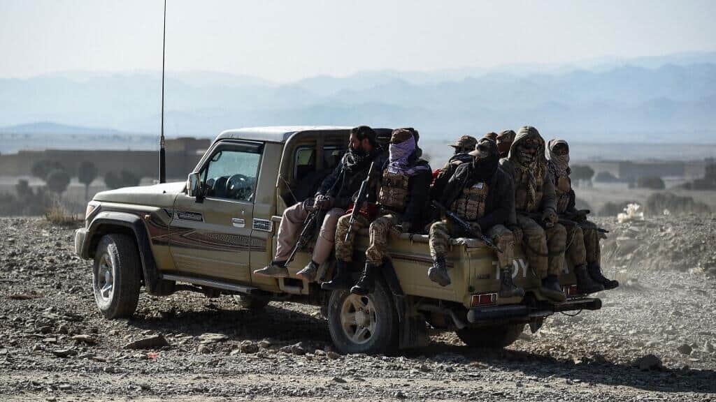 Tensions explosives : conflit Pakistan-Afghanistan annoncé Groupe de migrants transportés dans une camionnette dans un paysage désertique.