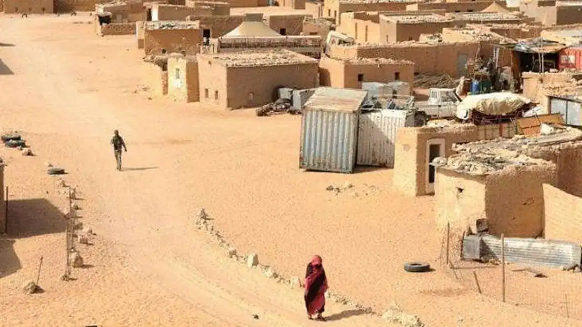 Village algérien avec maisons en terre et personnes dans le désert.