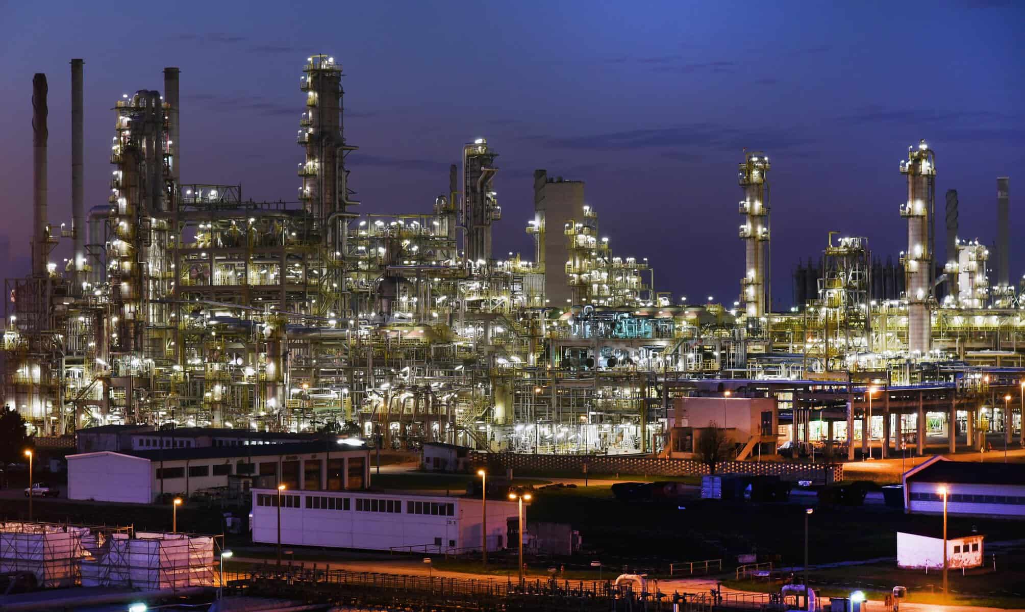 Usine de gaz et pétrole illuminée la nuit, infrastructure industrielle complexe.