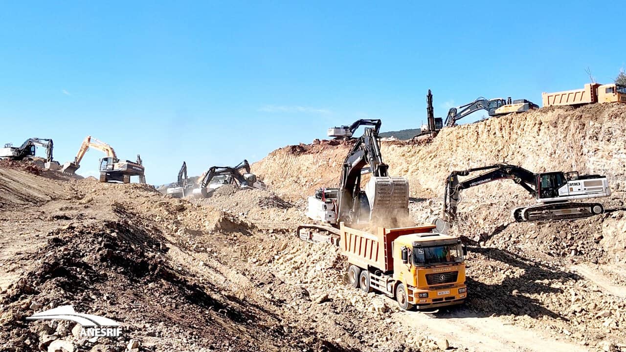 Excavatrices et camions sur un chantier de construction ferroviaire en Algérie.