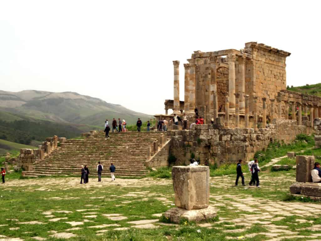 Ruines de Djemila, site historique en Algérie, avec visiteurs et paysages montagneux.