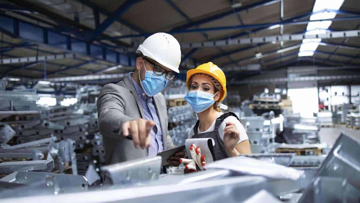 Italie 2026 : 43 300 Nouveaux Emplois pour Étrangers Deux travailleurs portant casque et masque dans une usine moderne.