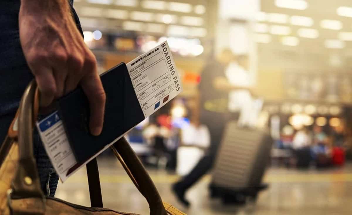 Ce sans-papiers reçoit une OQTF par erreur de l’État Passager tenant un billet d'embarquement à l'aéroport.