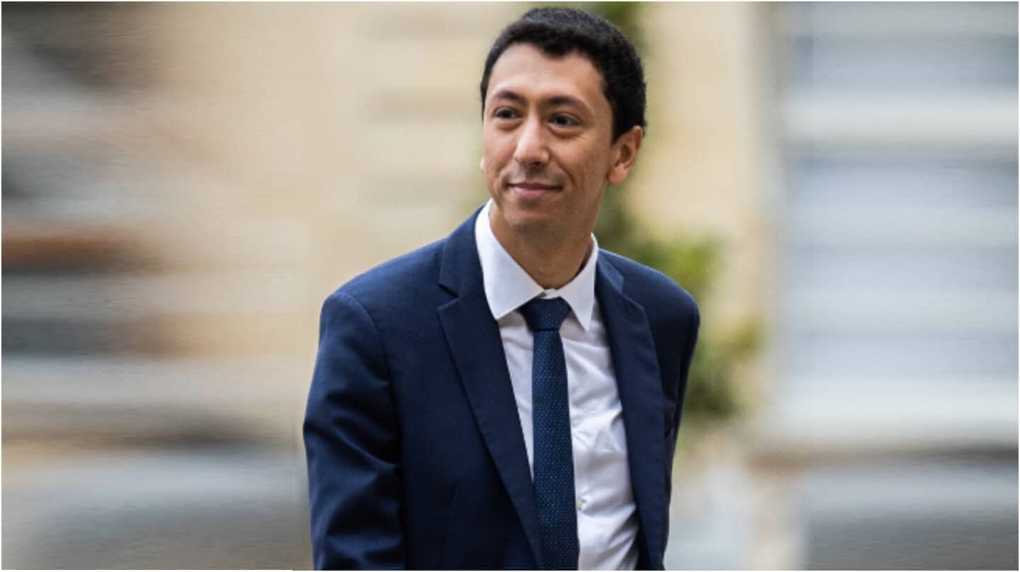Othman Nasrou Confronté à des Accusations de Racisme Othman Nasrou en costume lors d'une sortie officielle.