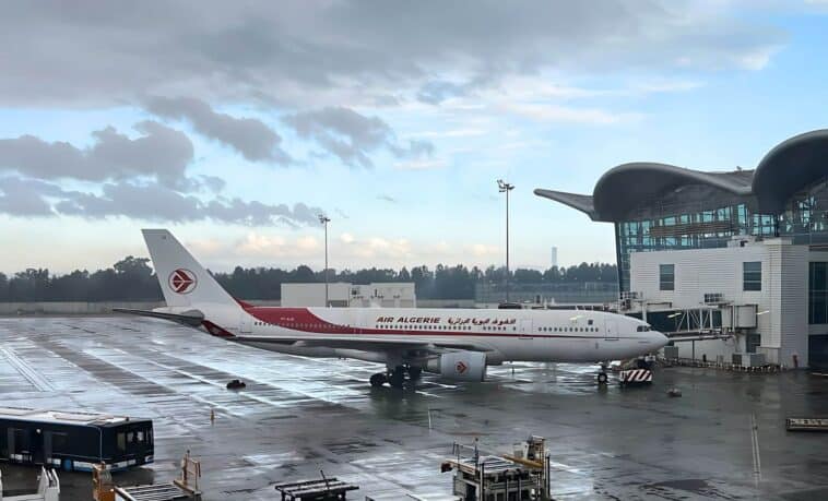Avion Air Algérie stationné à l'aéroport sous un ciel nuageux.