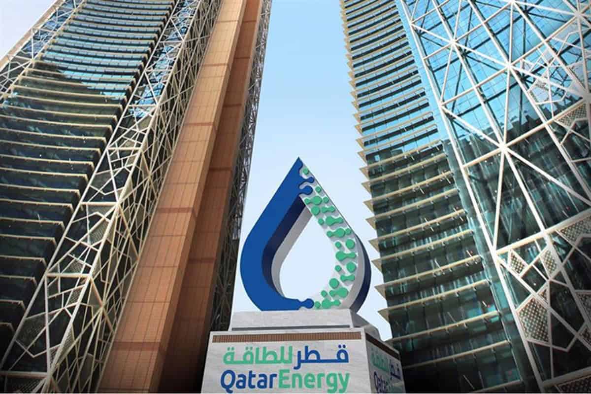 Logo de QatarEnergy entre deux gratte-ciel modernes en ville.