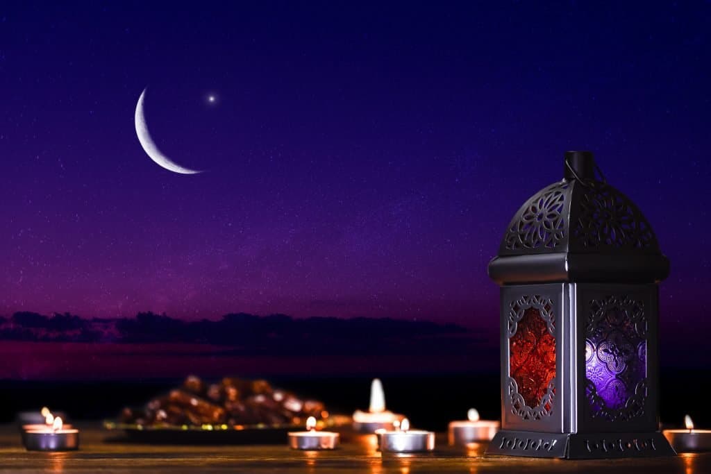 Défi Ramadan : Le Coran triomphe sur le superficiel Lanterne illuminée sous un ciel étoilé avec lune croissante.