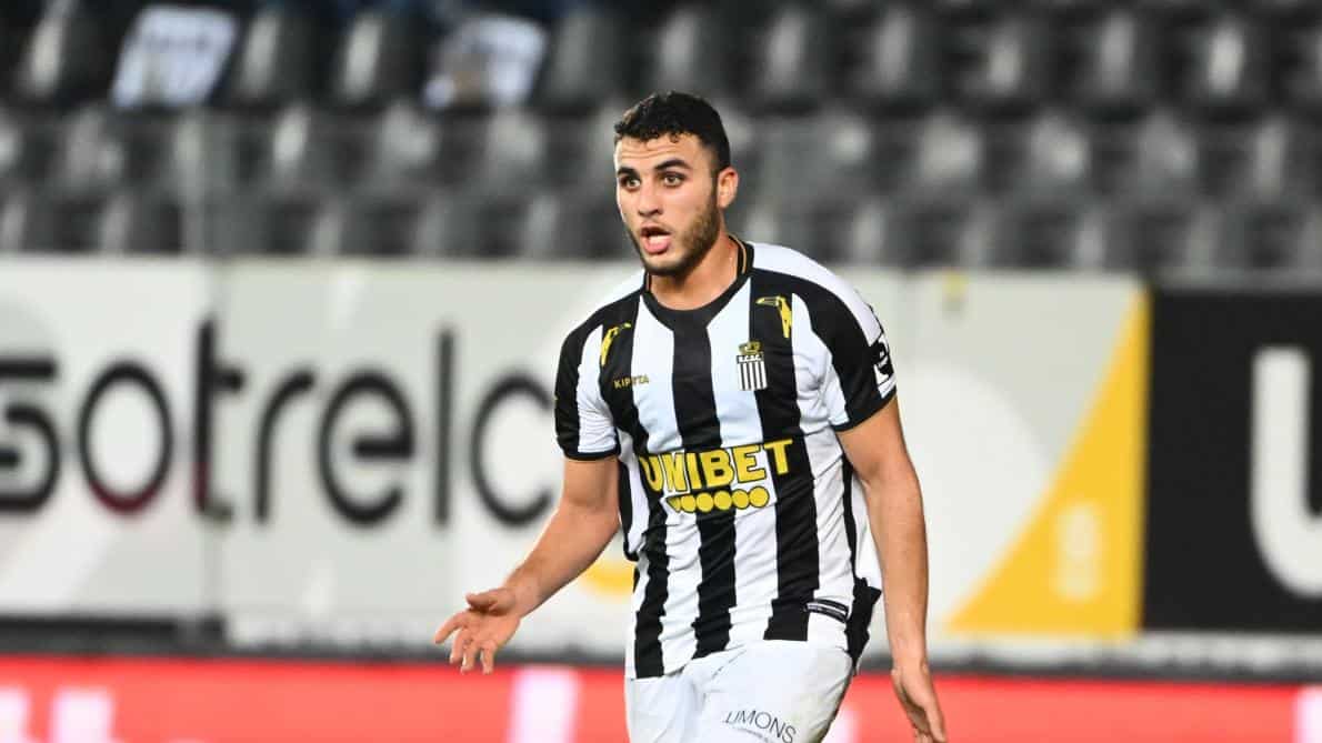Footballeur algérien portant maillot noir et blanc en match de football.