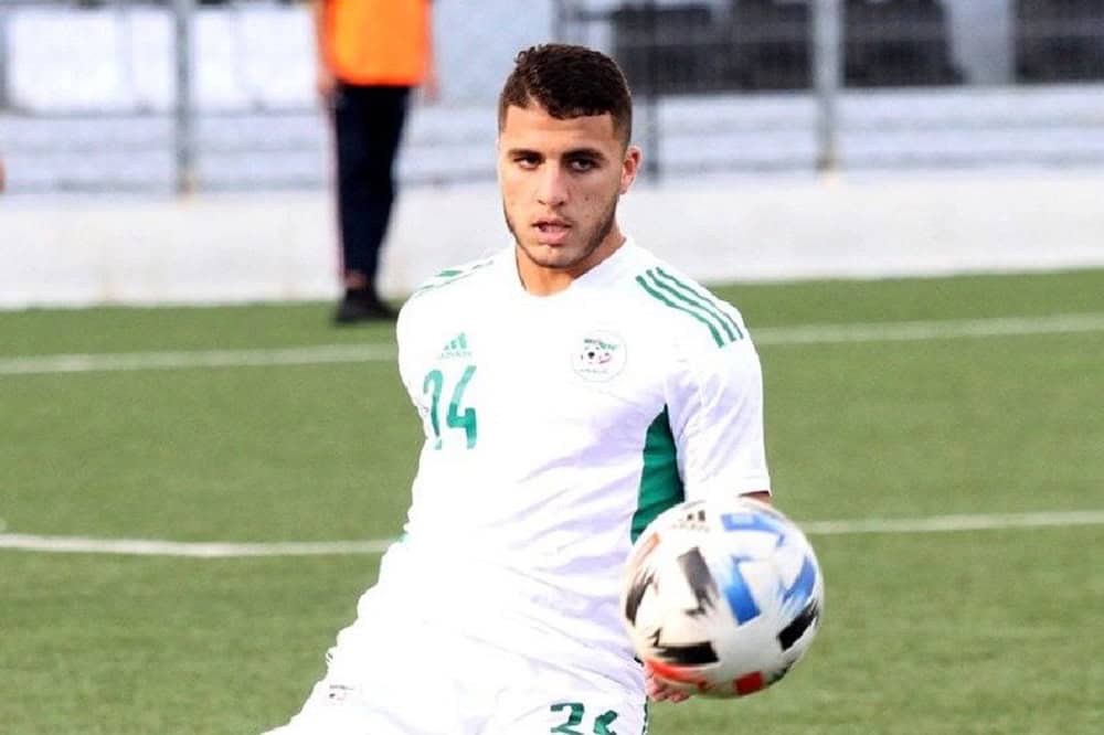 Jeune joueur algérien avec ballon sur le terrain de football.