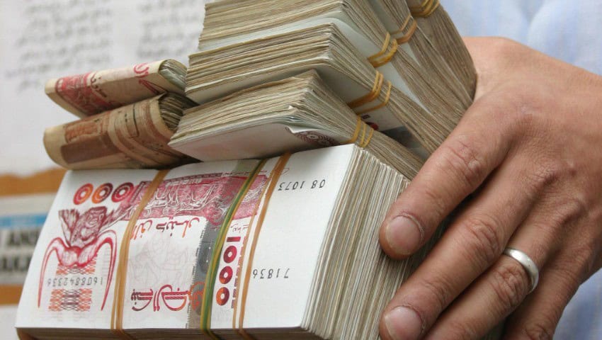 L’Algérie abandonne le cash : découvrez sa nouvelle stratégie Main tenant un gros paquet de billets de banque algériens.