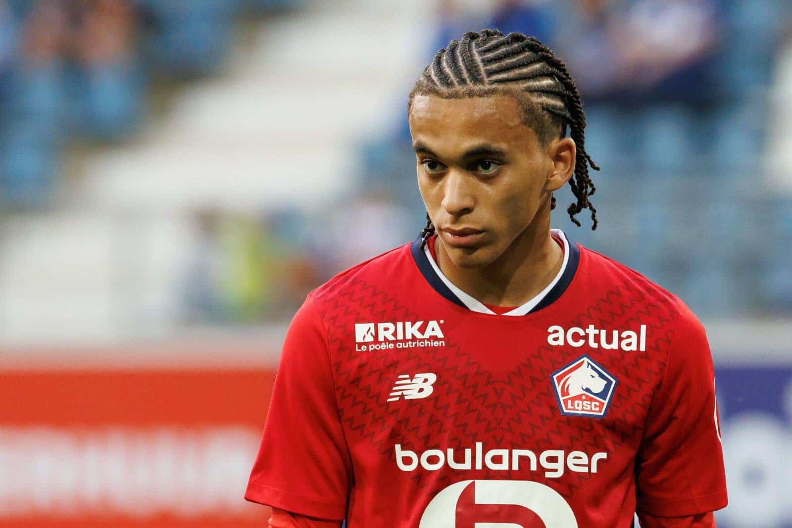 Ethan Mbappé en maillot rouge sur le terrain de football.