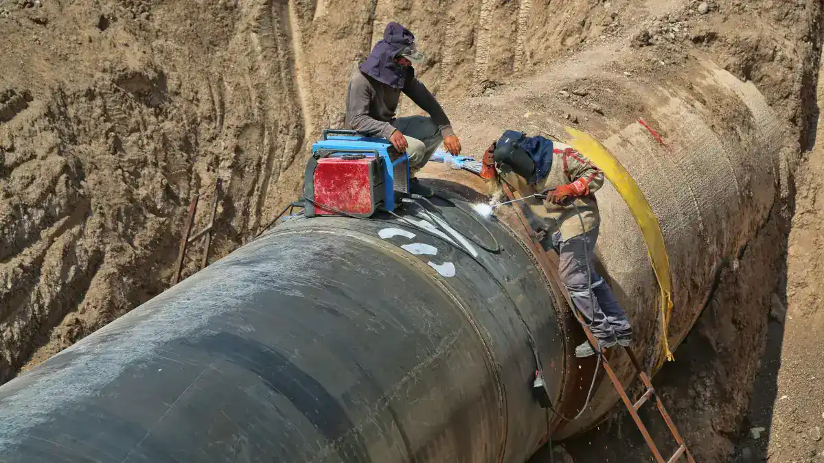 Travailleurs installant un pipeline dans un chantier souterrain en Algérie.