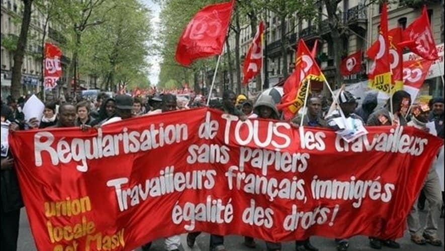 Emploi informel en France : nouvelles mesures Manifestation avec drapeaux rouges pour l'égalité des travailleurs.