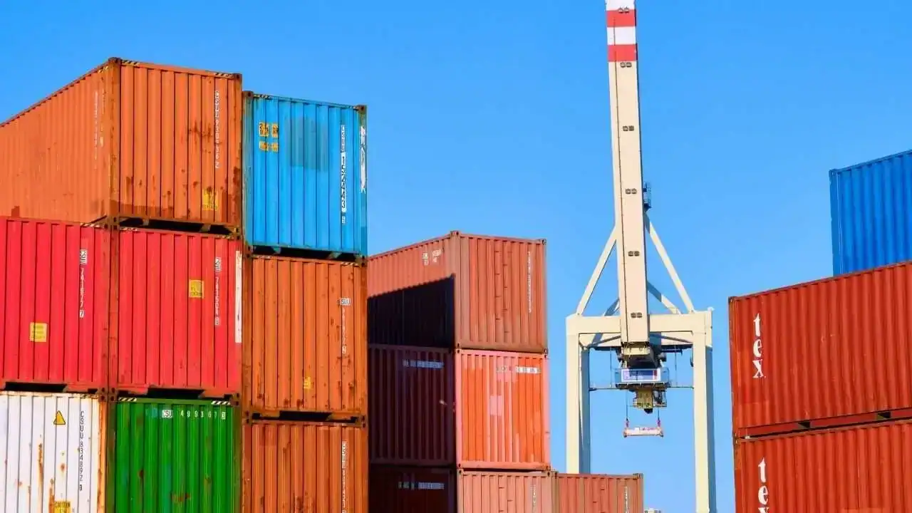 Algérie : Nouveau délai crucial pour le dépôt du PPI Conteneurs de fret colorés empilés avec grue portuaire en arrière-plan.