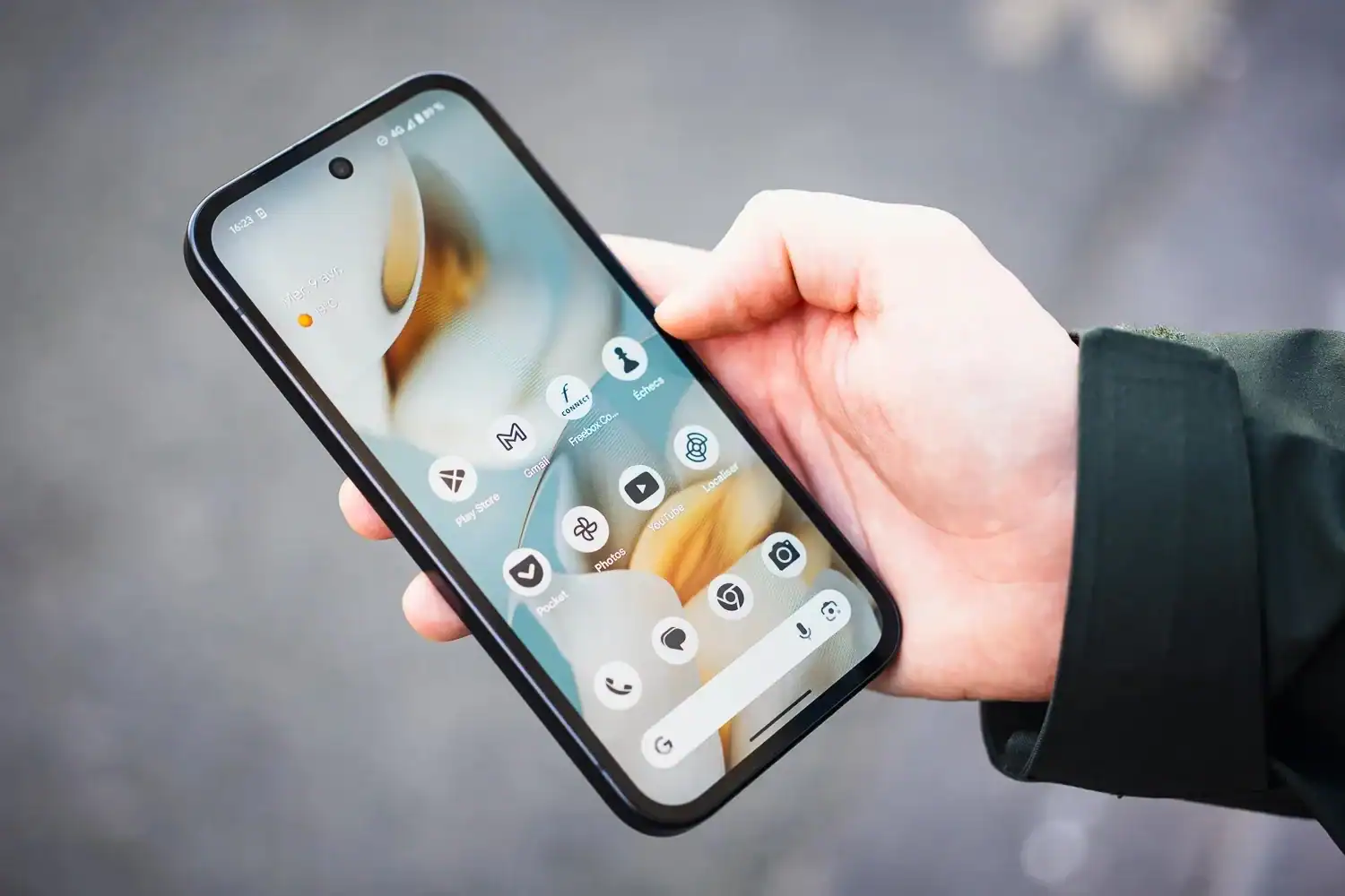 Algérie: Interdiction des smartphones à l’école dès 16 ans? Personne tenant un smartphone avec plusieurs icônes d'applications.