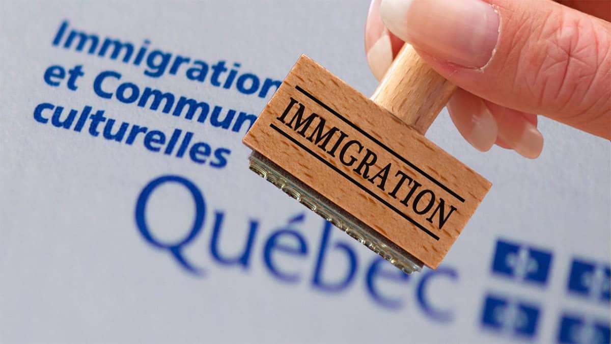 Changement majeur en immigration au Québec dévoilé Tampon en bois avec le mot 'Immigration' devant un logo du Québec.