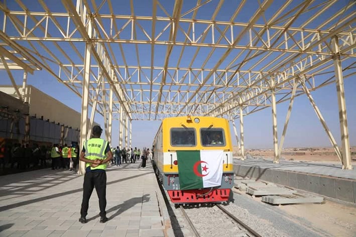 Lancement du train Tindouf-Méditerranée Train algérien avec drapeau national sous structure métallique en construction.