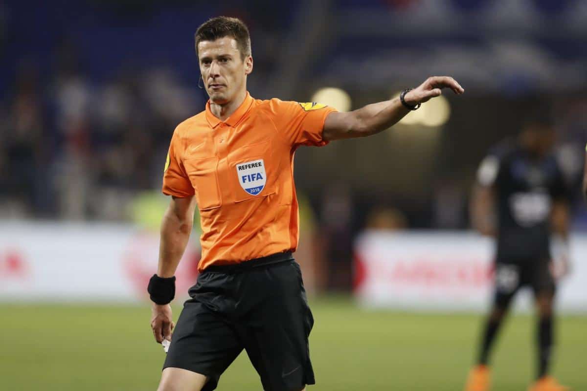 Arbitre FIFA en uniforme orange sur le terrain de football.