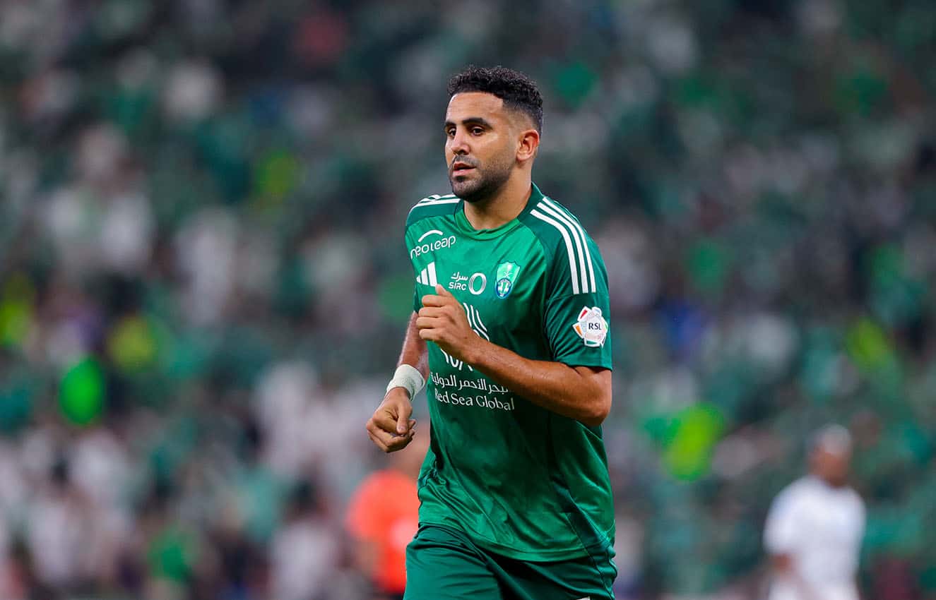 Riyad Mahrez en action lors d'un match Riyad Mahrez en maillot vert durant un match de football.
