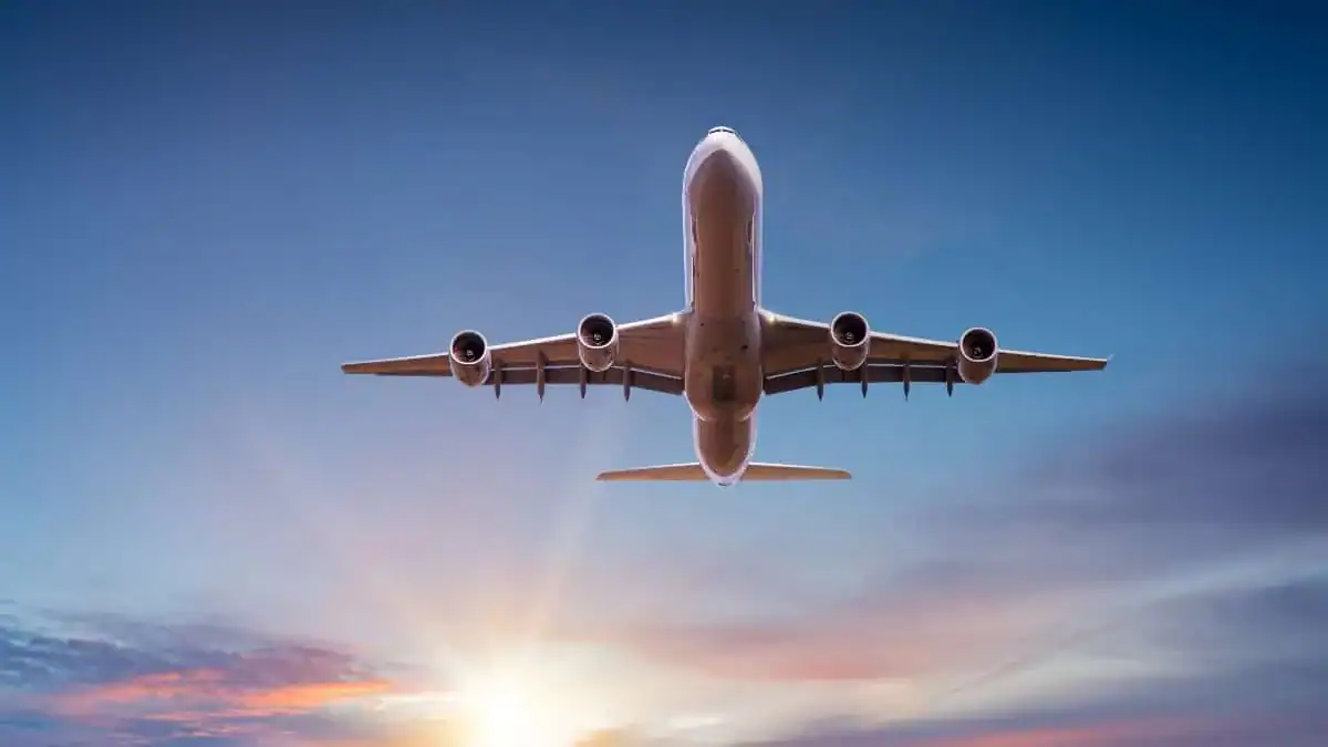Avion de ligne en vol avec coucher de soleil en arrière-plan.