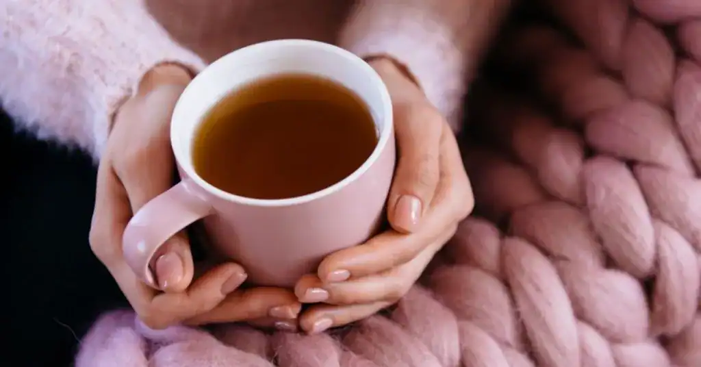 Votre Thé libère-t-il des toxines dans votre tasse ? Une personne tient une tasse de thé chaud dans ses mains.