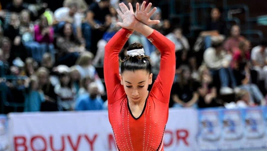 Jeune gymnaste en pleine performance lors d'une compétition.