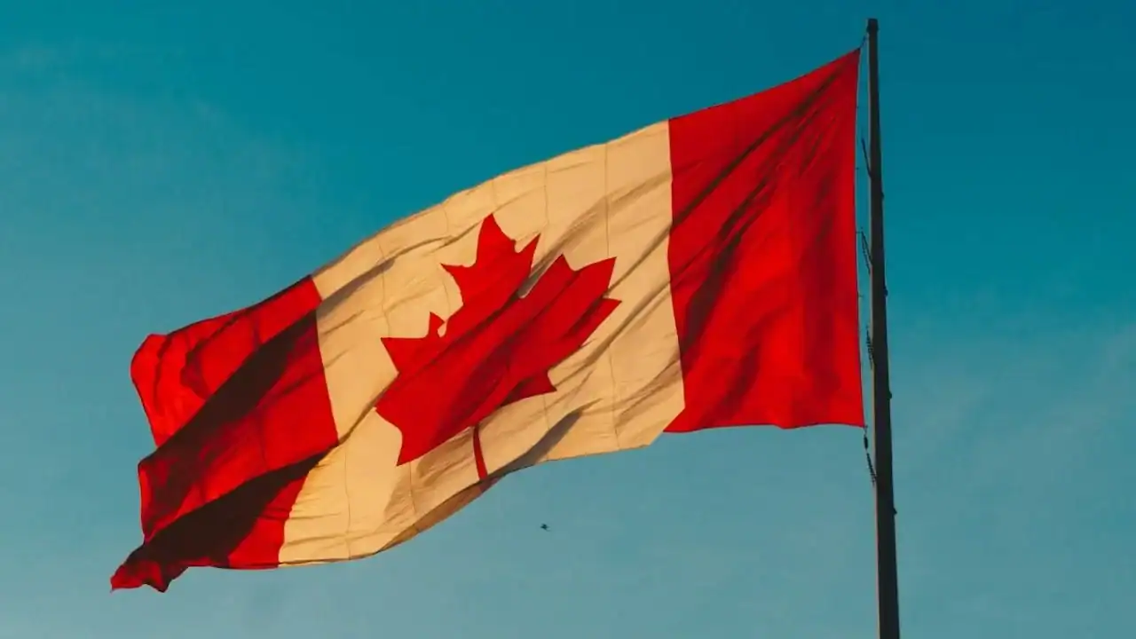 Entrée express au Canada : les hauts salaires désormais favorisés Drapeau du Canada flottant dans le ciel bleu clair.