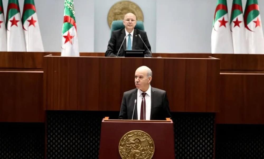 Algérie : Une retraite anticipée à 32 ans ? La réponse du ministre Ministre en séance parlementaire en Algérie avec drapeaux algériens.
