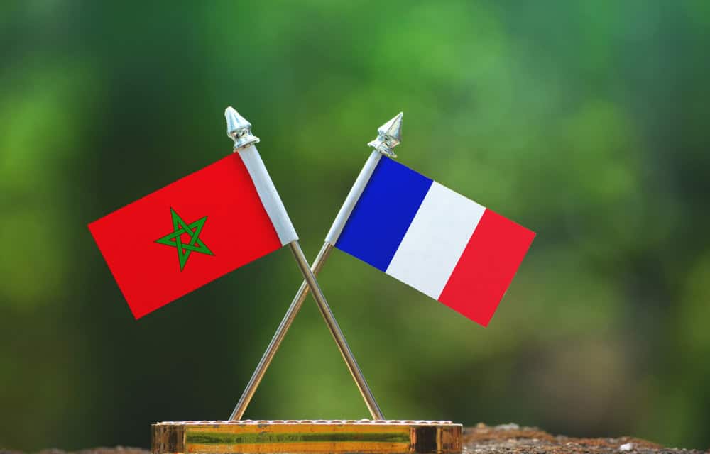 Drapeaux du Maroc et de la France croisés sur une base en bois.