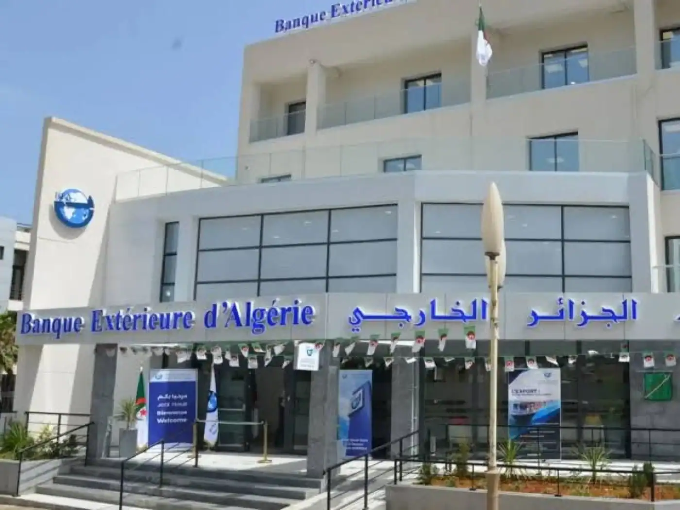 Algérie : interdiction de banques pour le commerce extérieur ? Agence de la Banque Extérieure d'Algérie avec drapeaux algériens.