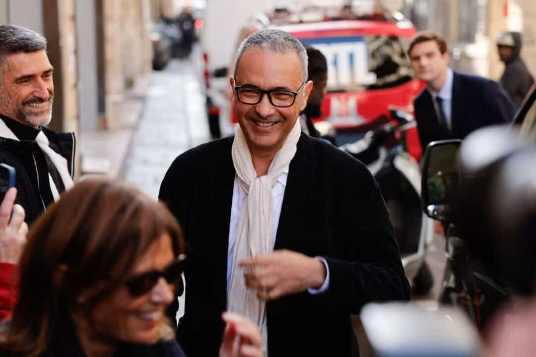 Kamel Daoud souriant entouré de personnes dans la rue.