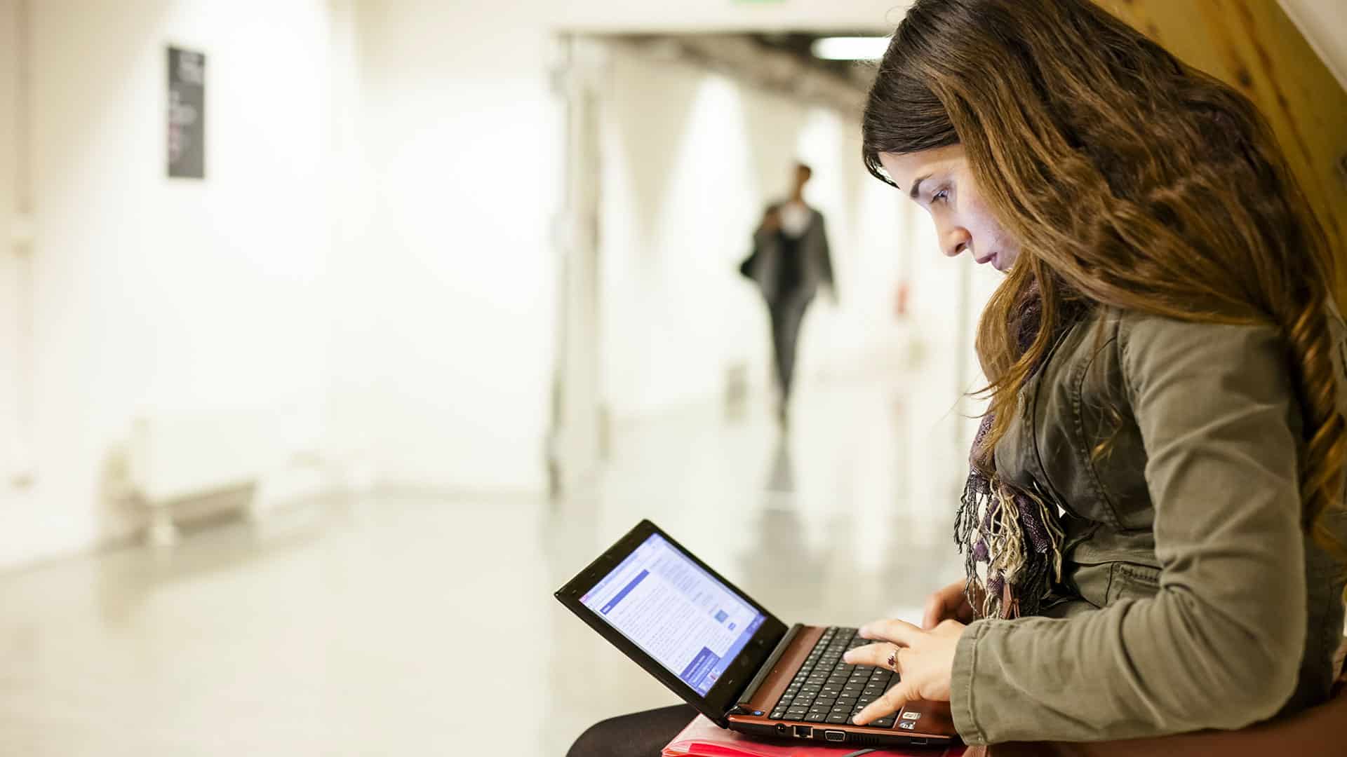 Titre de séjour en France : le parcours administratif complexe d’une doctorante algérienne Jeune femme utilisant un ordinateur portable dans un espace public.