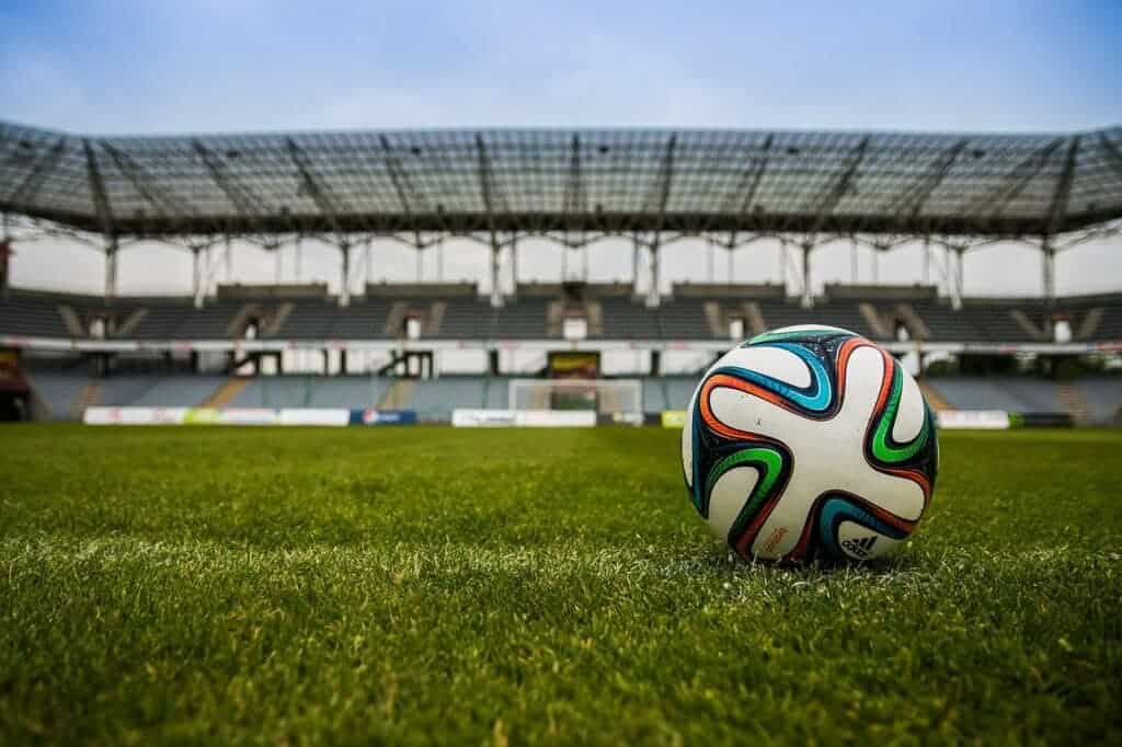 Ballon de football sur le terrain avec stade vide en arrière-plan.