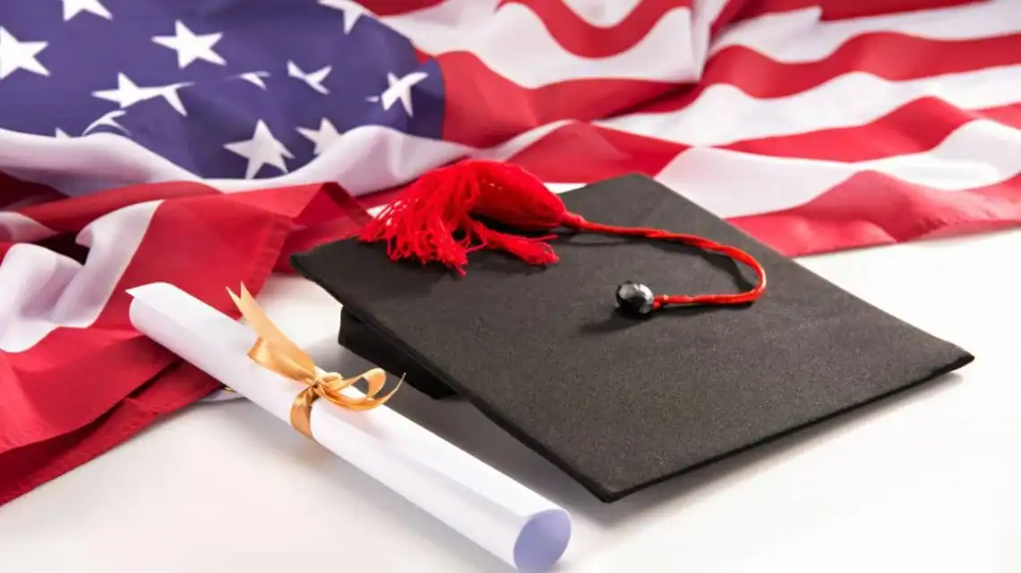 Les États-Unis proposent des bourses aux Algériens : comment l’obtenir ? Diplôme avec chapeau de graduation et drapeau américain en arrière-plan.