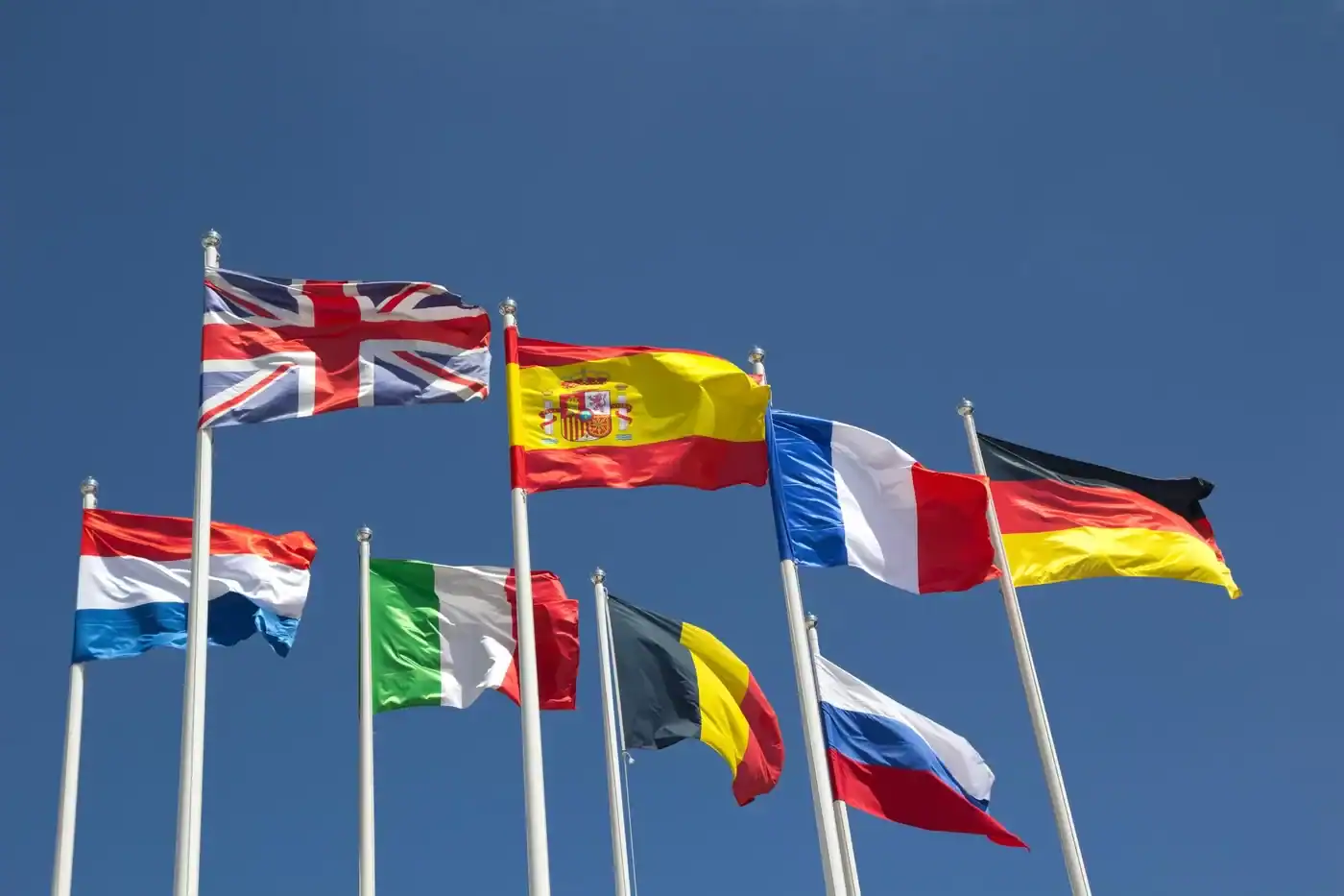 Drapeaux européens en plein vent Drapeaux de l'Europe flottant sous un ciel bleu clair.