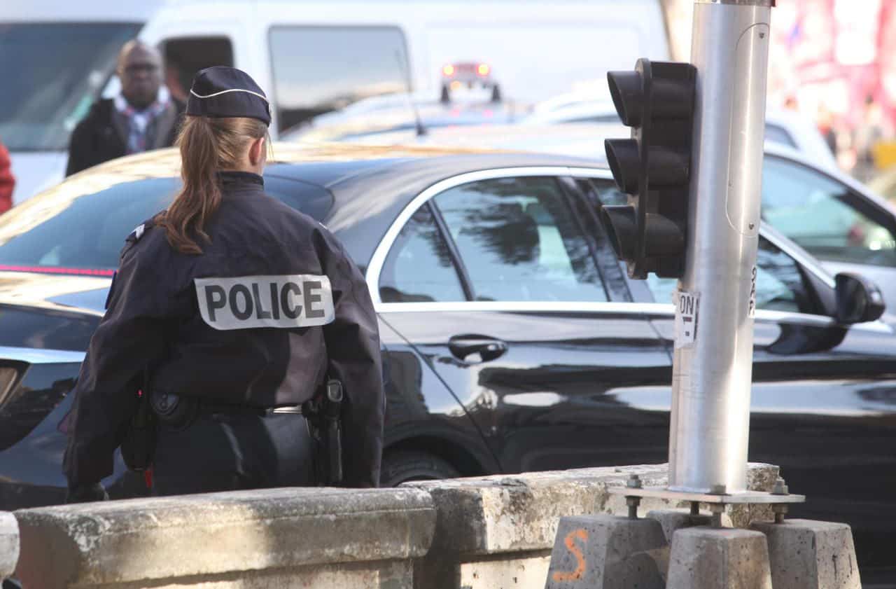Un Algérien vandale : des voitures ciblées en clinique Policière en uniforme à côté d'une voiture noire en ville.
