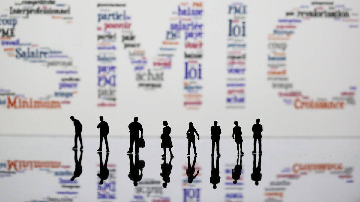 Smic en France : hausse confirmée des salaires en juin 2026 Groupe de personnes discutant devant un mur de mots liés au travail.