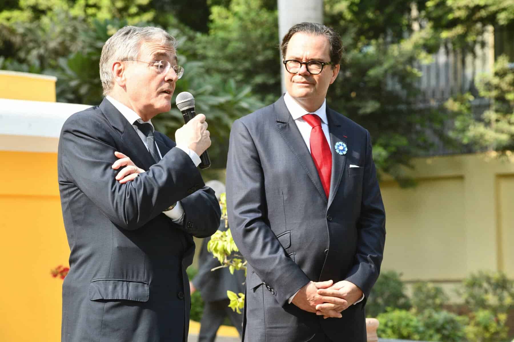 Deux hommes en costume lors d'une cérémonie en plein air.