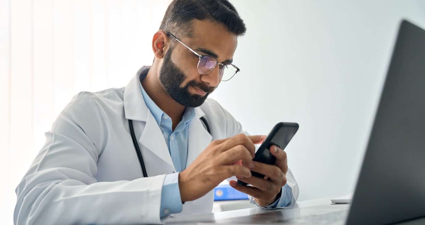 Médecins et réseaux sociaux : une interdiction nécessaire ? Médecin professionnel utilisant un smartphone dans un bureau moderne.