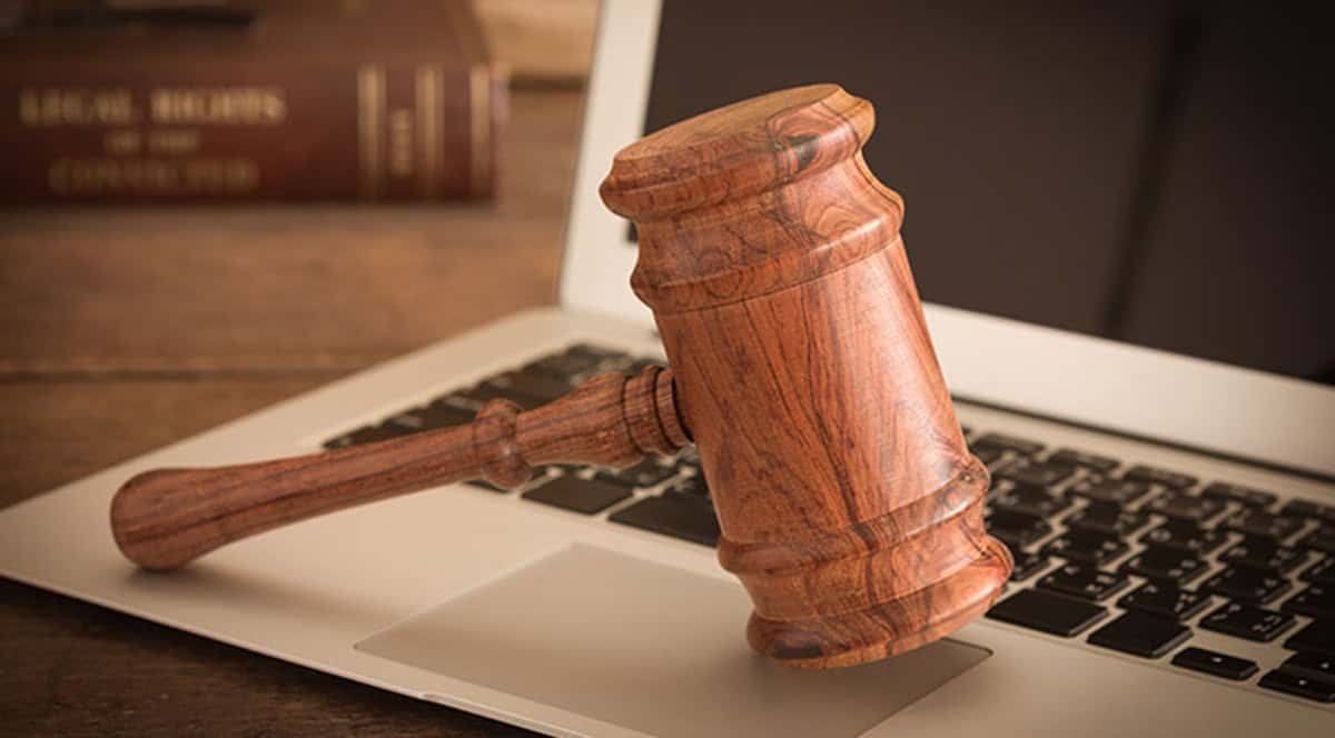 Procès-verbal et marteau de juge Marteau de juge posé sur un clavier d'ordinateur, symbolisant la justice et la législation.