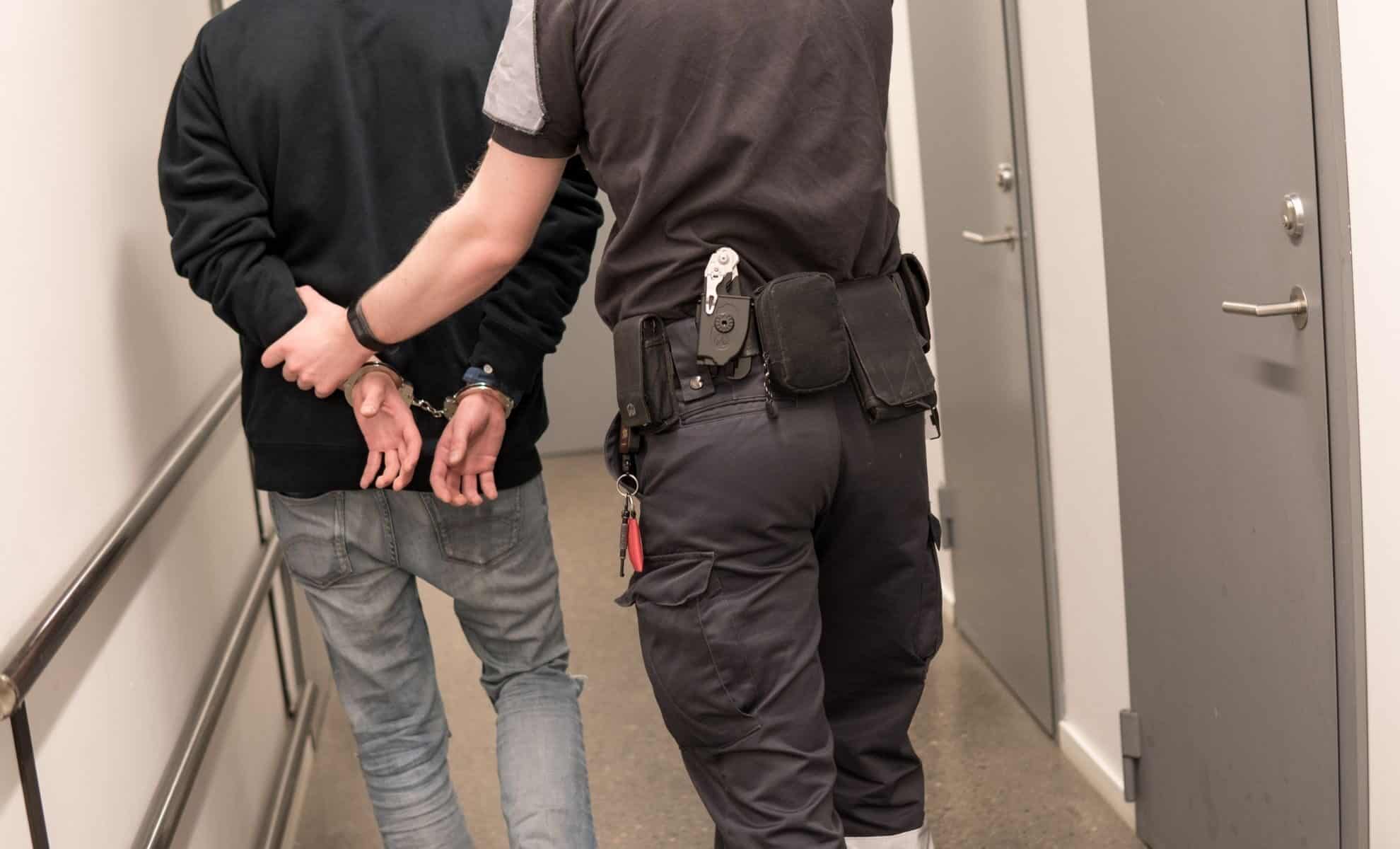 Algériens sans-papiers en France : un record d’arrestations Agent de police arrêtant un homme dans un couloir.